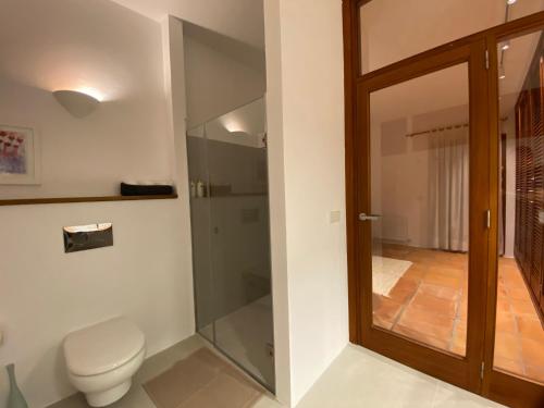 a bathroom with a toilet and a glass door at Can Poeta in Sant Carles de Peralta