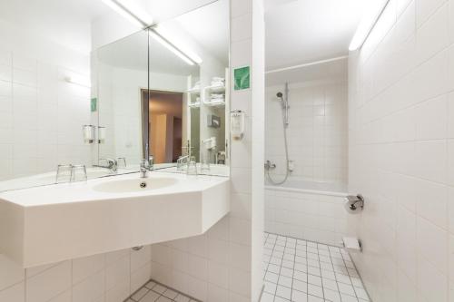 a white bathroom with a sink and a shower at Sure Hotel by Best Western Muenchen Hauptbahnhof in Munich