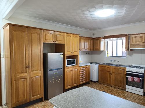 Η κουζίνα ή μικρή κουζίνα στο Spacious Queen Room in Large Merrylands Home with Sofa Bed - M2