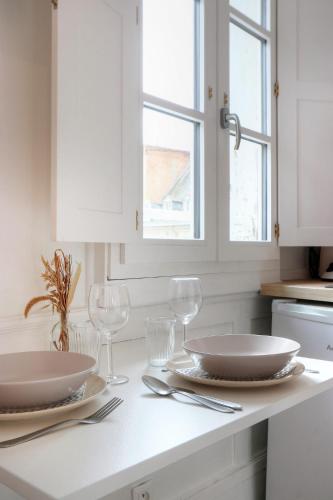 une cuisine blanche avec deux assiettes et des verres sur un comptoir dans l'établissement L'Artiste, à Rennes