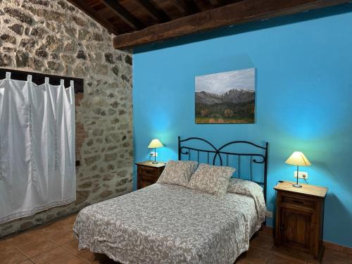 a bedroom with blue walls and a bed with two lamps at La Casona De Jaraiz in Jaraiz de la Vera