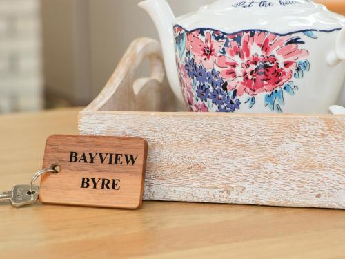 a key chain on a wooden table with a tray with a vase at Bayview Byre in Knock
