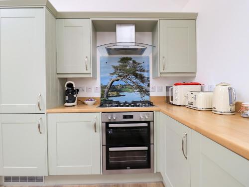 a kitchen with white cabinets and a stove top oven at Bayview Byre in Knock