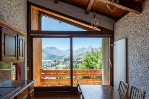 une cuisine avec une table et une grande fenêtre avec vue dans l'établissement Architect's Chalet with Stunning View - Close to Slopes and Shops, à La Toussuire
