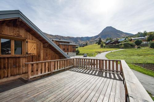 une terrasse en bois avec une maison et une montagne dans l'établissement Savoyard chalet of 300m in Albiez, à Albiez-Montrond