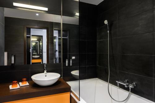a black bathroom with a sink and a shower at Art Hotel Szeged in Szeged