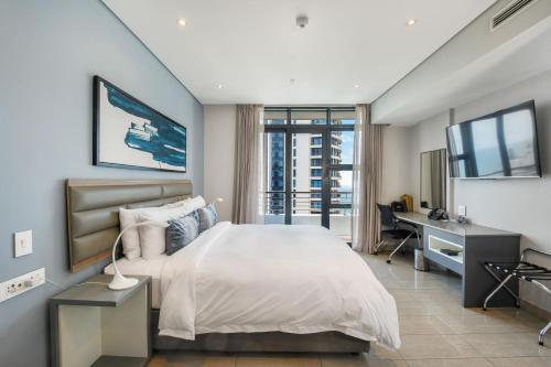 a bedroom with a bed and a desk and a television at The Capital Pearls Hotel in Durban