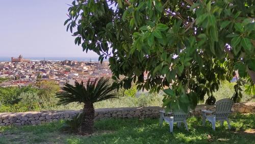 two chairs sitting under a tree looking at a city at Eremo delle Grazie in Ispica