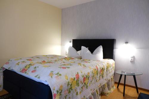 a bedroom with a large bed with a floral bedspread at Brocki's Hotel Stadt Hamburg in Parchim