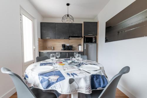 une table de salle à manger avec des chaises et une cuisine dans l'établissement Invitation aux doux souvenirs bretons - La Rose des Vents, à Arzon