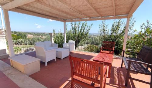 a patio with white chairs and tables and a roof at Eremo delle Grazie in Ispica