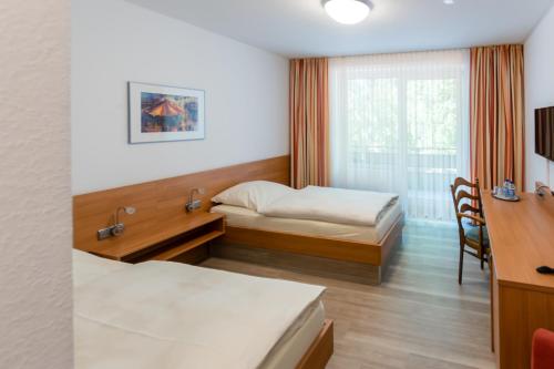 Habitación con 2 camas, escritorio y ventana. en Hotel Münnich, en Münster