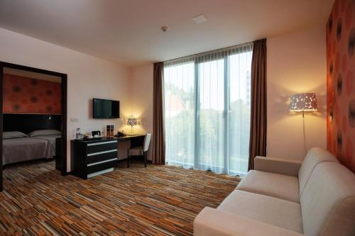 a hotel room with a couch and a bed and a desk at Art Hotel Szeged in Szeged