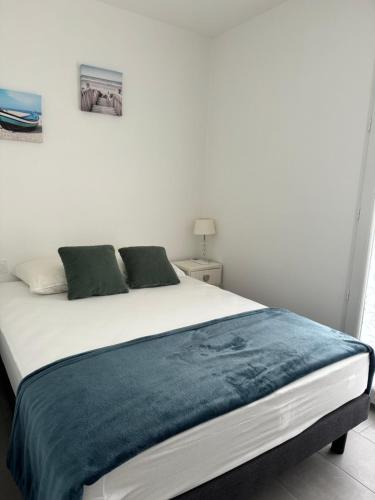 - un lit blanc avec une couverture bleue dans l'établissement Le Saphir - Plage du Mole, au Cap d'Agde