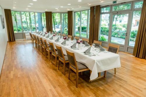 una sala de conferencias con una mesa larga con manteles blancos en Hotel Münnich, en Münster