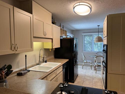 a kitchen with white cabinets and a black refrigerator at Hideaway in Southport