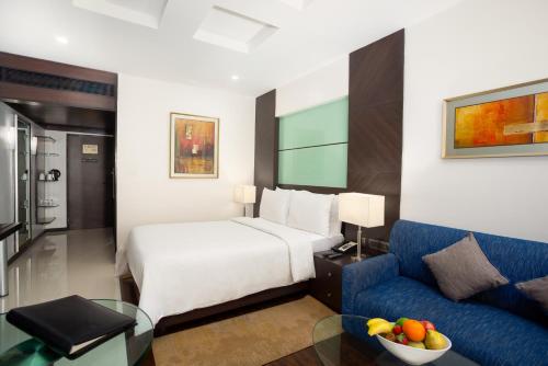 a hotel room with a bed and a blue couch at The Residency, Chennai in Chennai