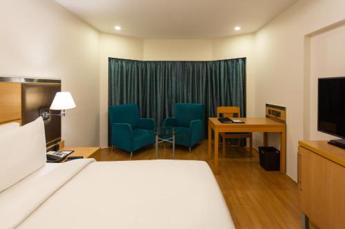 a hotel room with a bed and a table and chairs at The Residency, Chennai in Chennai