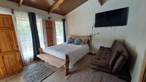 a bedroom with a bed and a chair and a television at S Natura Birding and Photography in Villa Mills