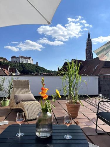 a patio with a table and wine glasses on a balcony at Über den Dächern der Landshuter Altstadt in Landshut