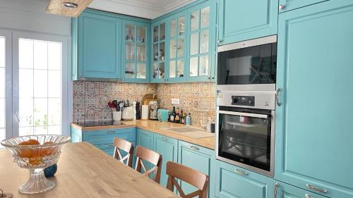 a kitchen with blue cabinets and a wooden table at Luxury on the beach apartment in Hanioti