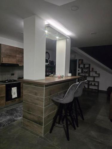 a kitchen with a counter and two stools in a room at Pepper Apartman Donji Miholjac in Donji Miholjac