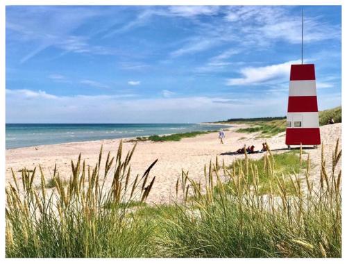 a red and white lighthouse on a sandy beach at Rørvig Bed & Kitchen in Rørvig