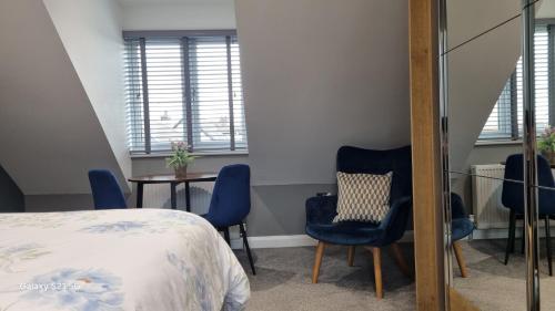 a bedroom with blue chairs and a bed and a table at Causeway Rooms in Ballybogy