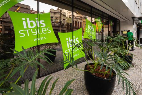 a store window with green signs in front of plants at ibis Styles Rio de Janeiro Botafogo in Rio de Janeiro