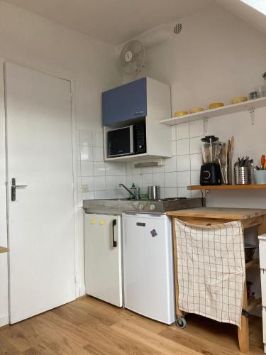 La cuisine est équipée d'un réfrigérateur blanc et d'un four micro-ondes. dans l'établissement Ravissant studio Montmartre Opéra, à Paris