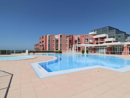 une piscine vide en face d'un bâtiment dans l'établissement Rez-de-jardin à Sète: 2 pièces, piscine, parking, terrasse - FR-1-472A-129, à Sète