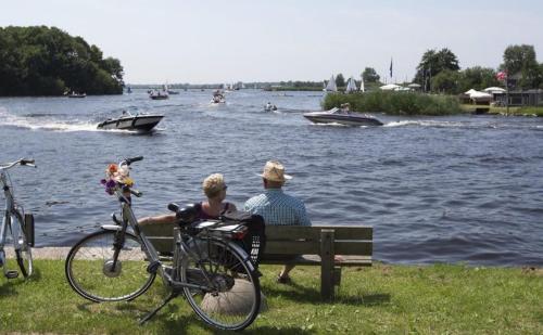 a man and a woman sitting on a bench next to a bike at Glamping de Hof van Eeden in Warmond