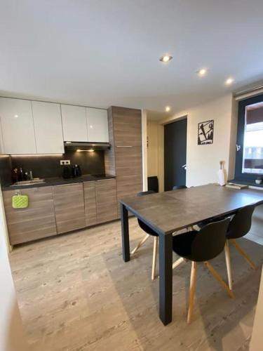 - une cuisine avec une table et des chaises noires dans la chambre dans l'établissement Alpe d'huez quartier jeux 50 m2-100 m des pistes, à Huez