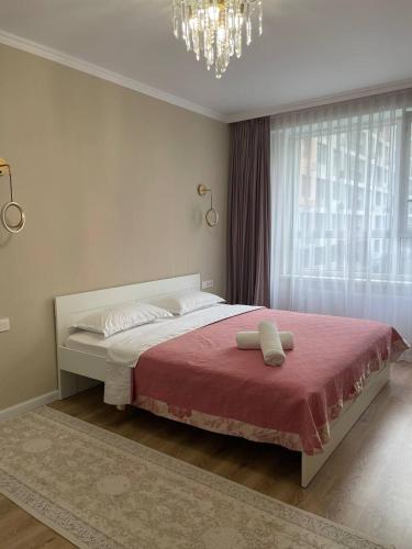 a bedroom with a bed with a red blanket and a chandelier at 3 bedroom apartment with 2 restroom in the Ala Park Business class in Almaty
