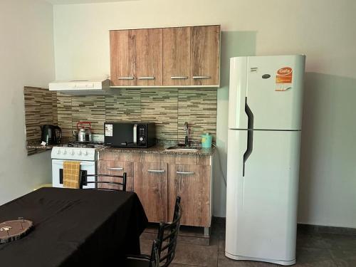 a kitchen with a white refrigerator next to a table at Complejo Aloe Vera C in Villa Dolores