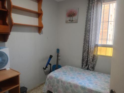 1 dormitorio con cama, ventana y guitarra en Rooms Malaga, en Málaga