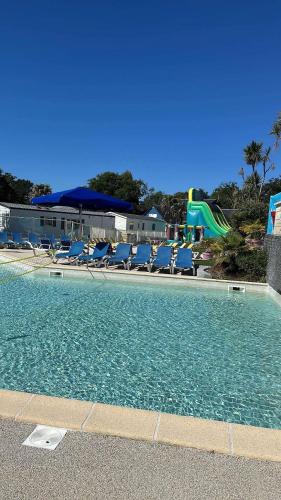 une piscine avec des chaises bleues et une aire de jeux dans l'établissement Le Domaine de Kerlann, à Pont-Aven