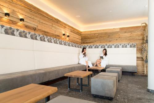 two women sitting on a bench in a restaurant at Berghotel Schmittenhöhe - 2000m in Zell am See