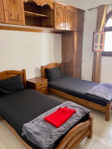 a bedroom with two beds with wooden cabinets and a red towel at Red oasis in Dahab