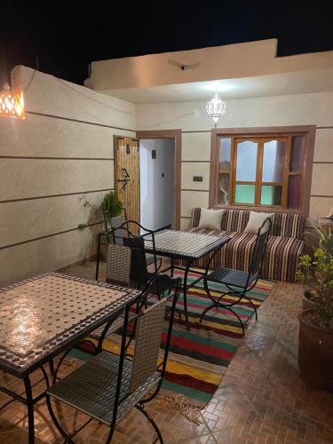 a patio with tables and chairs and a couch at Dar Mgouna Roses in Kalaat MGouna