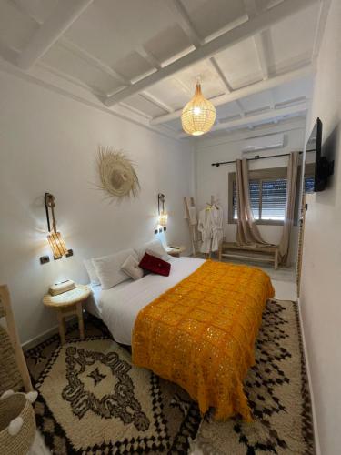 a bedroom with a large bed with an orange blanket at Dar Mgouna Roses in Kalaat MGouna