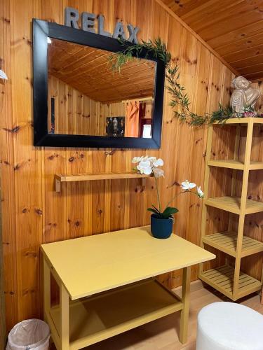 a mirror on a wooden wall with a yellow table at Auberge Restaurant les Aiguilles Rouges in Hérémence
