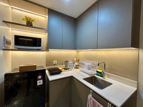 a small kitchen with a sink and a microwave at Gold Coast Apartment PIK Luxury Sea View by stay with E in Jakarta