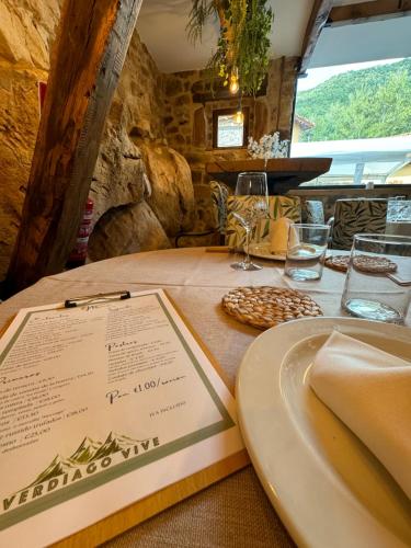 a table with a menu and wine glasses on it at El Hotel & SPA de Verdiago in Verdiago