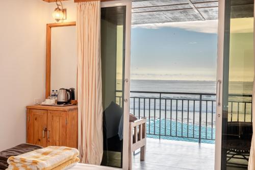 a room with a balcony with a view of the ocean at Simrose in Agonda