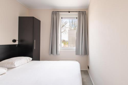 a bedroom with a bed and a window at Kompas Camping Nieuwpoort in Nieuwpoort