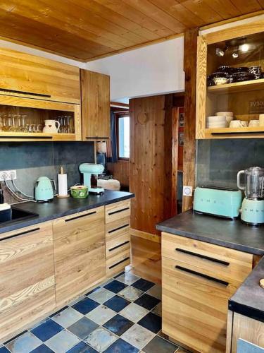 - une cuisine avec des placards en bois et un sol en damier dans l'établissement Le Nan Ste, à Megève