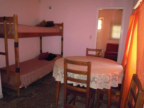 a room with two bunk beds and a table and chairs at Casa Bichi in Villa Gesell