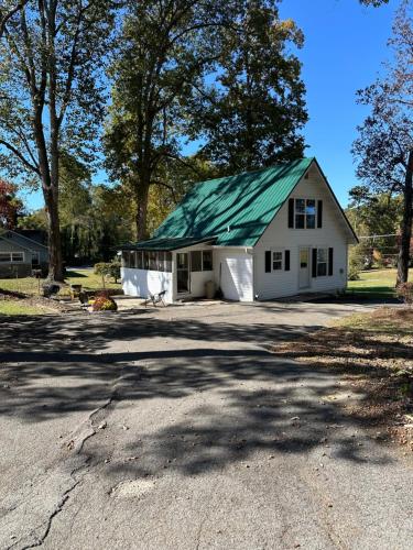a white house with a green roof on a driveway at Cottage on the Hill Knoxville in Knoxville