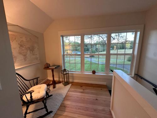 a living room with two windows and a chair at Cottage on the Hill Knoxville in Knoxville